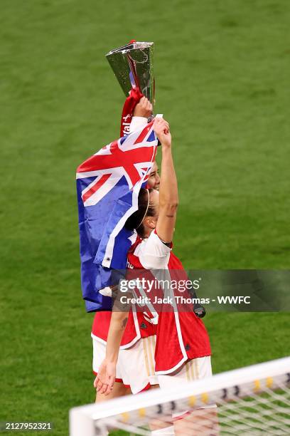 Caitlin Foord, Kyra Cooney-Cross and Steph Catley of Arsenal celebrate victory with the trophy and an Australian flag following the FA Women's...