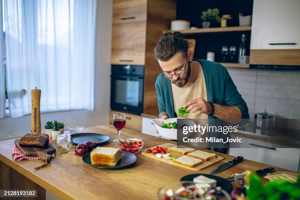 man prepares a club sandwich in the kitchen - making a sandwich stockfoto's en -beelden