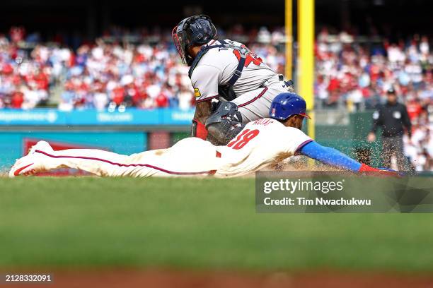 Johan Rojas of the Philadelphia Phillies slides past Chadwick Tromp of the Atlanta Braves to score during the seventh inning at Citizens Bank Park on...