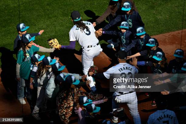 Crawford of the Seattle Mariners and Ty France shake hands with fans before the game against the Boston Red Sox at T-Mobile Park on March 31, 2024 in...