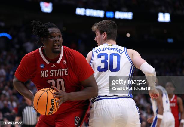 Burns Jr. #30 of the North Carolina State Wolfpack controls the ball as Kyle Filipowski of the Duke Blue Devils defends in the Elite 8 round of the...