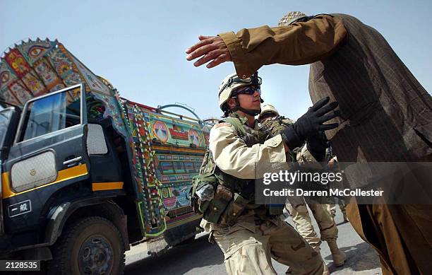 Soldier with the 82nd Airborne searches an Afghan man at a traffic checkpoint conducted by the U.S. Army July 1, 2003 on the outskirts of Kandahar,...