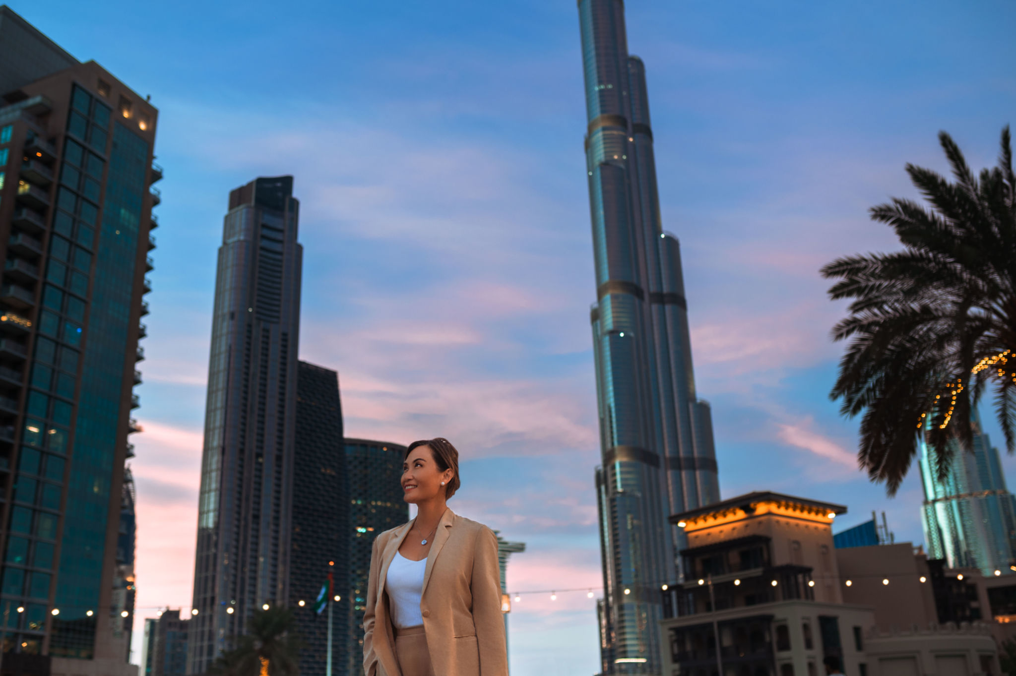 Cheerful asian businesswoman looking up, admiring ultramodern skyscrapers in city center at night Cheerful asian businesswoman looking up, admiring ultramodern skyscrapers in city center at night