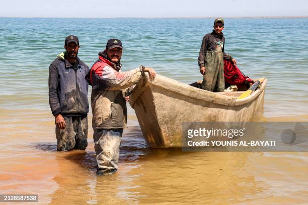 Fishermen stand by a boat near the shore of Lake Hamrin in Iraq's Diyala province on April 3, 2024 which had previously dried up in a drought and...