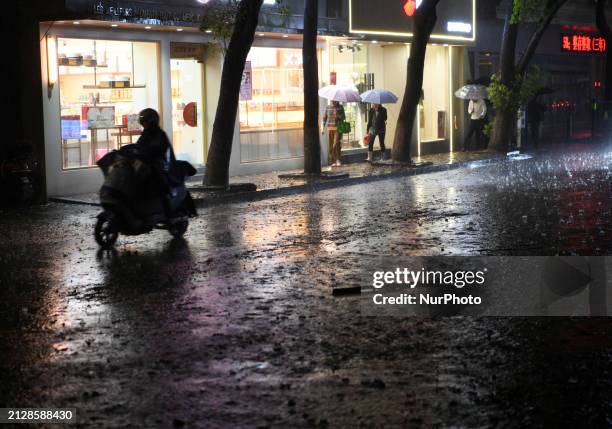 People are riding electric bikes on a street during heavy rain in Nanchang, Jiangxi Province, China, on April 2, 2024.