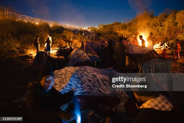 Migrants at a camp between concertina wire and the river after crossing the US-Mexico border through the Rio Grande in El Paso, Texas, US, on...