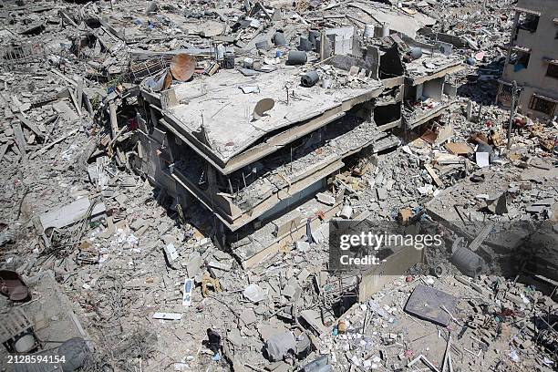 Palestinian man walks on building rubble in a devastated area around Gaza's Al-Shifa hospital on April 3 amid the ongoing conflict between Israel and...