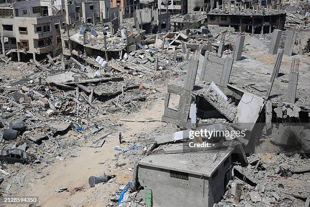 Palestinian youth walks amid rubble in a devastated area around Gaza's Al-Shifa hospital on April 3 amid the ongoing conflict between Israel and the...