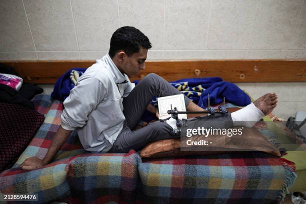 An injured Palestinian man reads the Koran as he sits on a bed at the Shuhada al-Aqsa Hospital in Deir el-Balah in the central Gaza Strip on April 3...