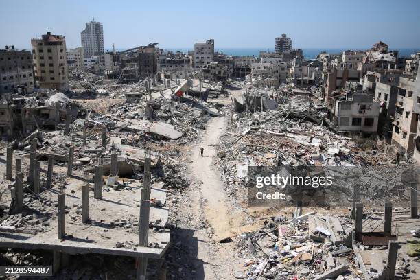 Man pushes a bycicle along as he walks amid building rubble in the devastated area around Gaza's Al-Shifa hospital on April 3 amid the ongoing...