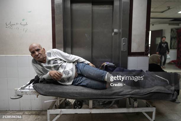 An amputated Palestinian man lies on a bed in the corridor at the Shuhada al-Aqsa Hospital in Deir el-Balah in the central Gaza Strip on April 3 amid...