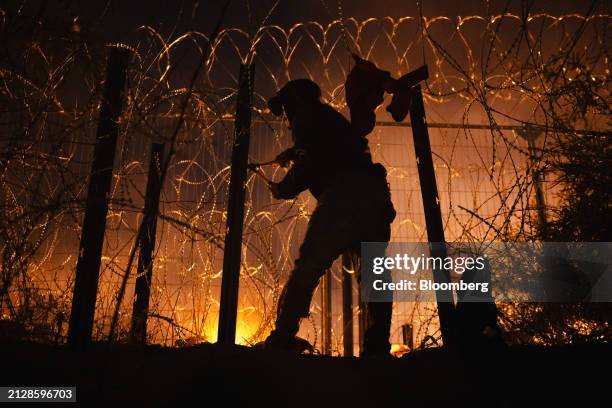 Migrant cuts through concertina wire after crossing the US-Mexico border through the Rio Grande in El Paso, Texas, US, on Tuesday, April 2, 2024. The...