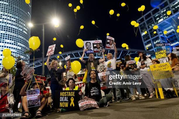 Families of hostages held in the Gaza Strip and supporters hold signs and photos of hostages, as they are releasing yellow balloons during a...