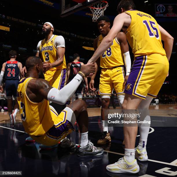 LeBron James of the Los Angeles Lakers is helped up by teammates during the game against the Washington Wizards on April 3, 2024 at Capital One Arena...