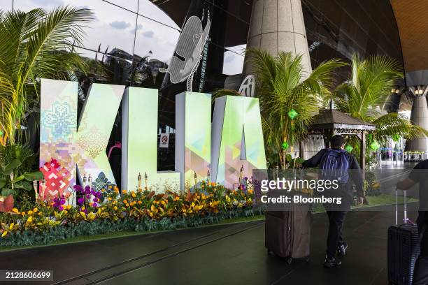 Passengers walk past a signage for the Kuala Lumpur International Airport in Sepang, Selangor, Malaysia, on Wednesday, April 3, 2024. After posting...