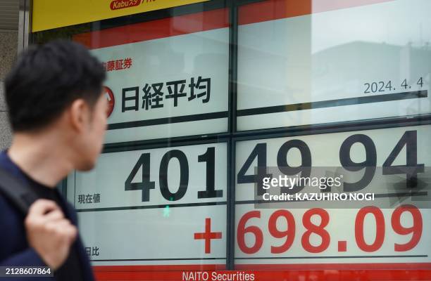 Man looks at an electronic board showing a share price of the Nikkei index of the Tokyo Stock Exchange in Tokyo on April 4, 2024.