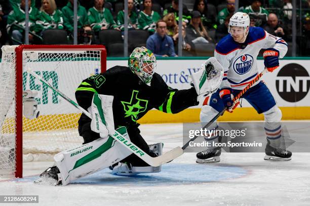 Dallas Stars goaltender Jake Oettinger catches the puck with his glove hand as Edmonton Oilers left wing Zach Hyman looks on during the game between...