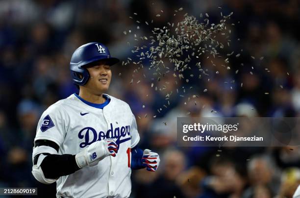 Shohei Ohtani of the Los Angeles Dodgers is showered with sunflower seeds by Teoscar Hernandez after hitting a solo home run during the seventh...