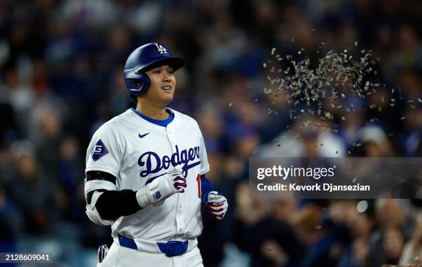 Shohei Ohtani of the Los Angeles Dodgers is showered with sunflower seeds by Teoscar Hernandez after hitting a solo home run during the seventh...