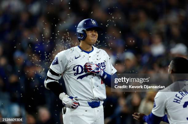 Shohei Ohtani of the Los Angeles Dodgers is showered with sunflower seeds by Teoscar Hernandez after hitting a solo home run during the seventh...