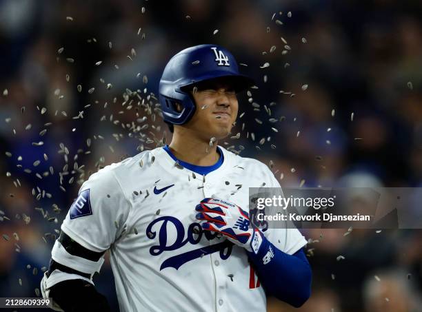 Shohei Ohtani of the Los Angeles Dodgers is showered with sunflower seeds by Teoscar Hernandez after hitting a solo home run during the seventh...