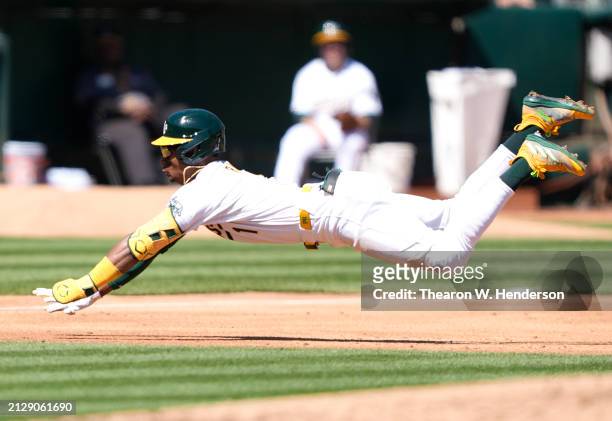Esteury Ruiz of the Oakland Athletics dives into third base with a triple against the Cleveland Guardians in the bottom of the third inning on March...