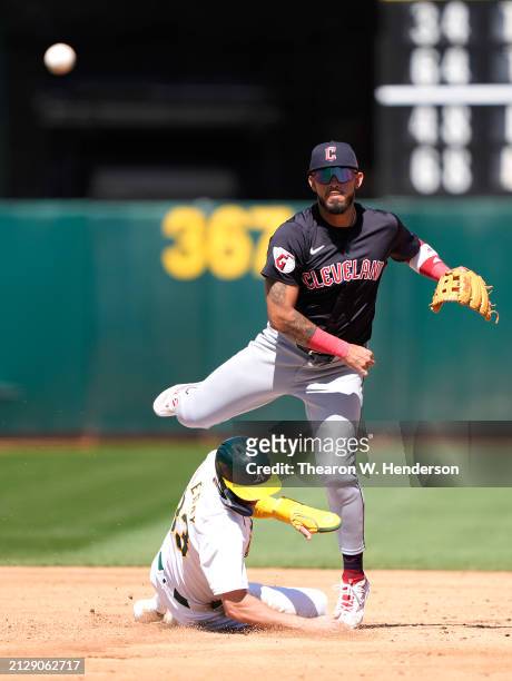 Gabriel Arias of the Cleveland Guardians completes the double-play throwing to first base over the top of JJ Bleday of the Oakland Athletics in the...