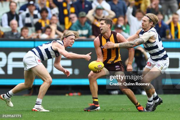 Luke Breust of the Hawks handballs whilst being tackled by Tom Stewart of the Cats during the round three AFL match between Hawthorn Hawks and...