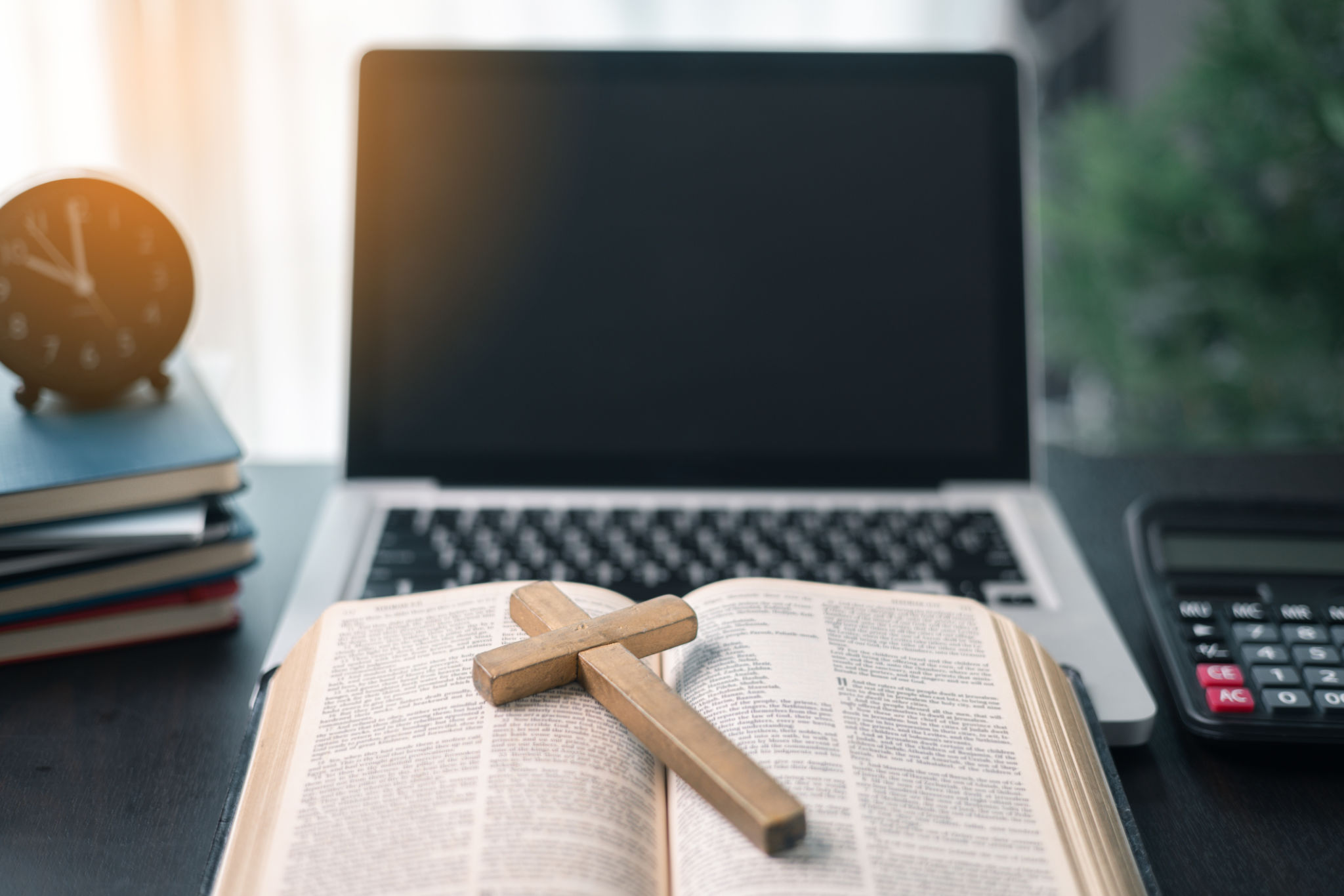 Cross on bible and laptop in online study bible concept. Holy Bible concept for modern religious education, podcast or help with hearing for blind studying Cross on bible and laptop in online study bible concept. Holy Bible concept for modern religious education, podcast or help with hearing for blind studying