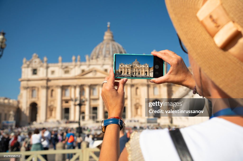 Una mujer toma una foto con un teléfono inteligente de la Basílica de San Pedro en la Ciudad del Vaticano, Roma, Italia