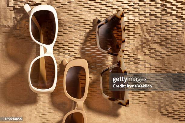 set of fashion collection sunglasses - horn rim sunglasses on abstract geometric background made of brown wrapping paper with sunlight. - colección de la moda fotografías e imágenes de stock