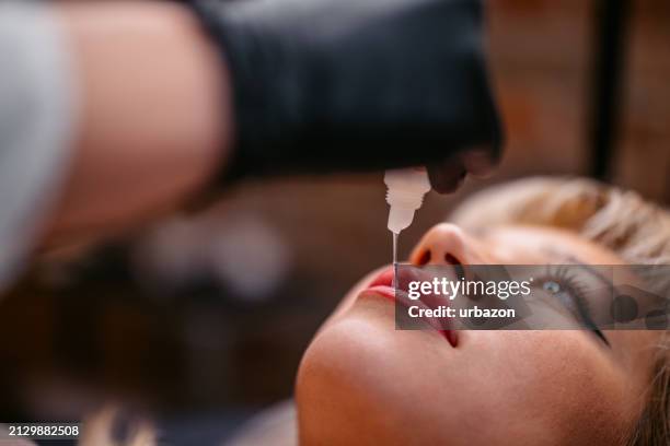 female beautician tattooing her client's lips at a beauty salon - lip tattooing stock pictures, royalty-free photos & images