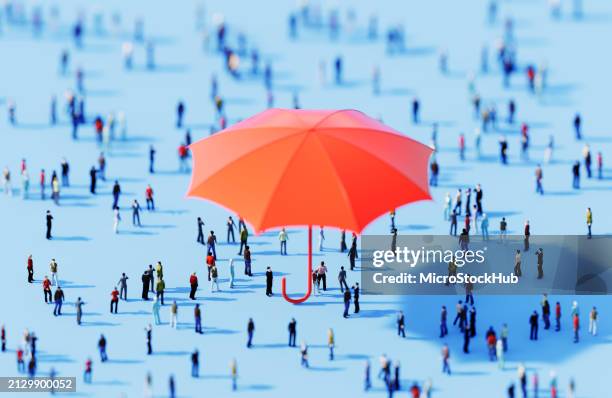 folla umana che circonda un oggetto ombrello su sfondo blu - demografia foto e immagini stock