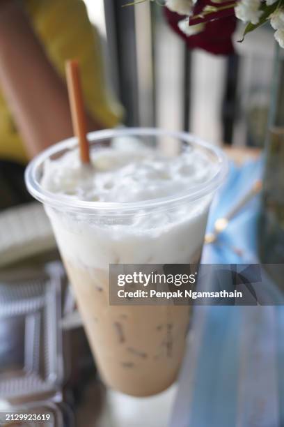 close up view of ice cubes in cold brewed coffee cappuccino in plastic cup put on wooden desk blurred background, drink beverage - sugary coffee drink stock pictures, royalty-free photos & images