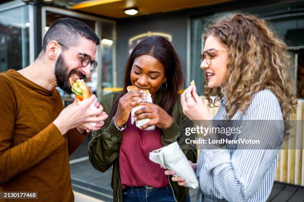 freunde essen fast food auf der straße - streetfood stock-fotos und bilder