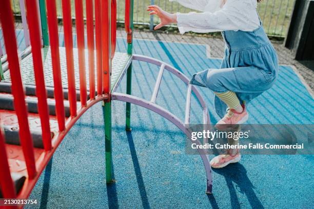 a child climbs up a purple metal ladder in a playpark - playground slide ladder stock pictures, royalty-free photos & images