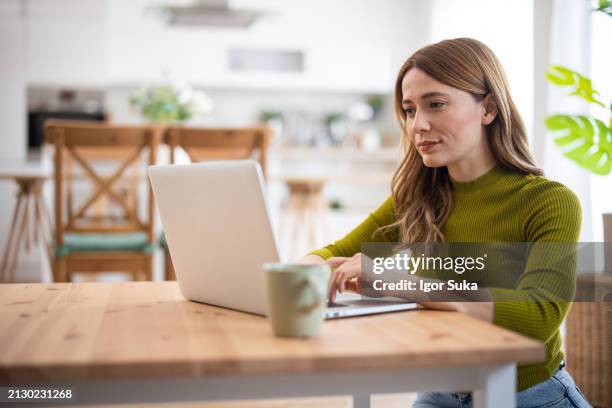 frau mit laptop, während sie zu hause sitzt - bloggen stock-fotos und bilder