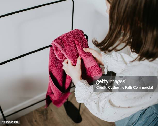 a child dries her hands on a pink hand towel - towel dispenser stock pictures, royalty-free photos & images