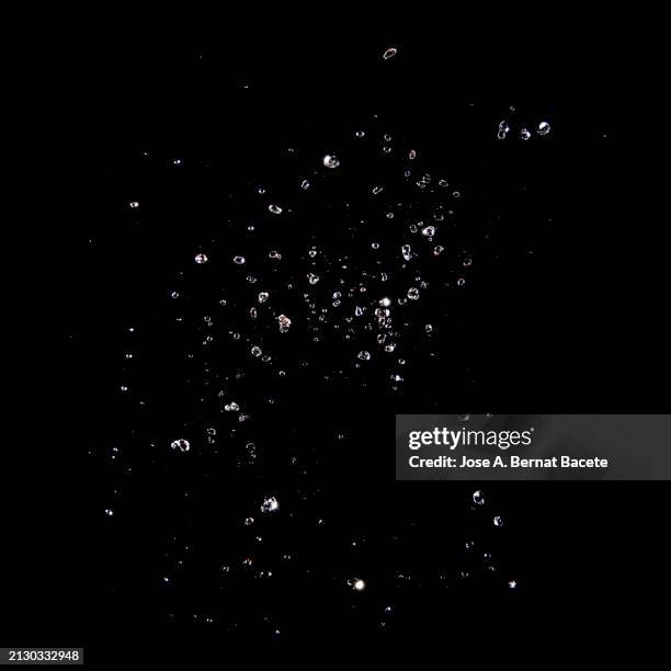 splashes and drops of water in motion on a black background. - gota de lluvia fotografías e imágenes de stock