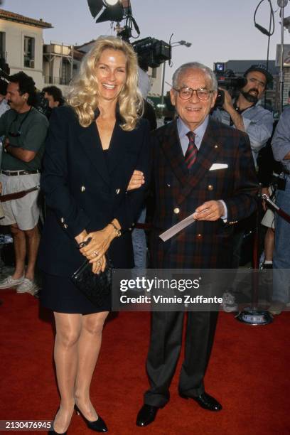 American film producer Martha De Laurentiis, wearing a black suit, and her husband, Italian film producer Dino De Laurentiis, who wears a plaid...