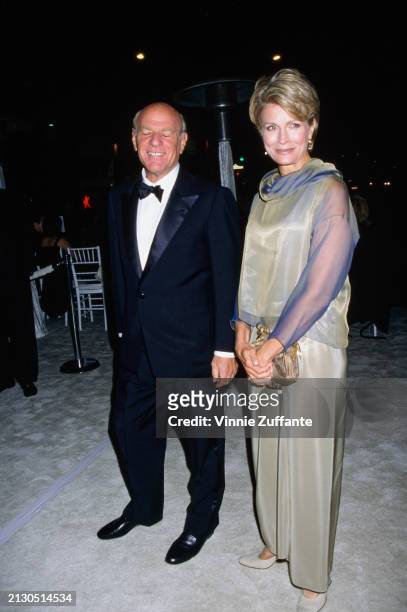 American businessman Barry Diller, wearing a tuxedo and bow tie, and American actress Candice Bergen, who wears a pale green evening gown with blue...