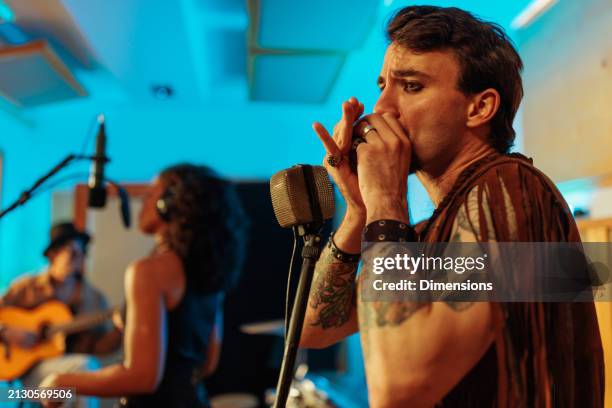 funky artist playing harmonica in the white room - harmonica stock pictures, royalty-free photos & images