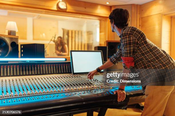 music producer creating music while singer sings in the studio - producer stock pictures, royalty-free photos & images