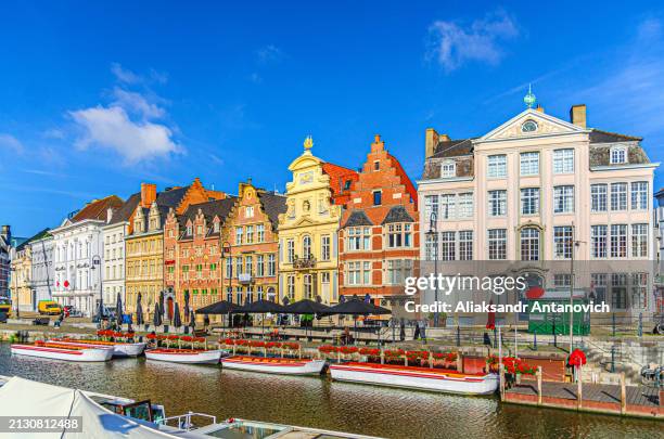 Ghent city historical center, tourists boats near Korenlei Corn Wheat Quay on Leie river bank, row of old colorful buildings on Lys river embankment, East Flanders province, Flemish Region, Belgium