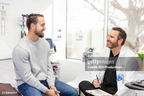 male doctor and male patient smile at each other - cuidados de saúde primários imagens e fotografias de stock