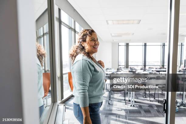 female teacher smiles at unseen student - entering stock pictures, royalty-free photos & images