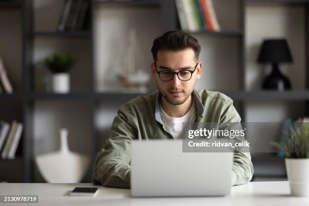 portrait of young man sitting at his desk in the office - bring your own device stock pictures, royalty-free photos & images