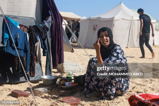 Palestinian woman gestures as she sits outside a tent at a makeshift camp for displaced people in Rafah in the southern Gaza Strip on April 4 amid...