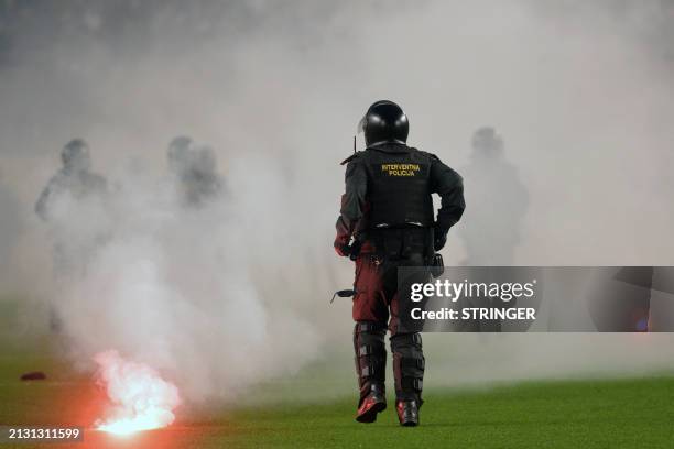 Croatian police officers walk on the field during clashes with members of Hajduk Split football team's ultra fan base, known as the Torcida, at the...