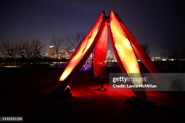 March 31 - A park visitor explores the 'Drawn to the Flame' art installation, illuminated canoes forming a campfire, at Trillium Park in Toronto. The...